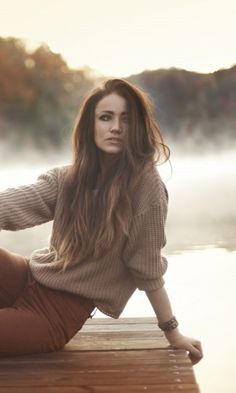 a woman sitting on top of a wooden dock