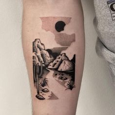 a man's arm with a black and white landscape tattoo on the left forearm