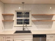 a kitchen with white cabinets and open shelving above the dishwasher is shown