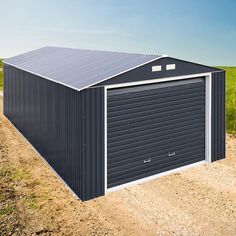 a large metal garage sitting on top of a dirt road next to a green field