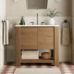 a bathroom with a sink, mirror and towels on the rack in front of it