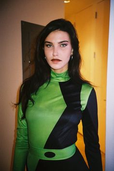 a woman in a green and black dress posing for the camera with her hands on her hips