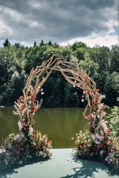 an outdoor wedding ceremony with flowers and greenery on the ground, surrounded by water