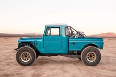 a blue truck parked on top of a dirt field