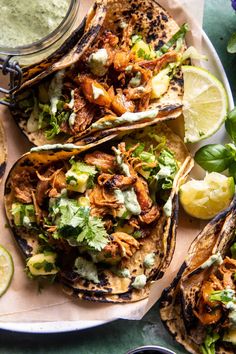 three tacos with chicken, avocado and cilantro sauce on the side