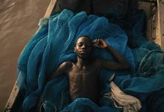 a man laying on top of a blue blanket in a boat