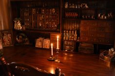 a lit candle sits on a wooden table in front of an old bookcase and other items