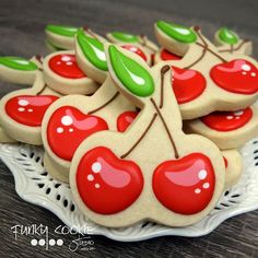 cookies decorated like cherries on a plate with green leaves and red berries are ready to be eaten