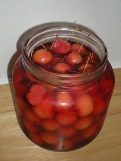 a jar filled with cherries sitting on top of a wooden table