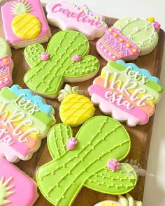 some decorated cookies are sitting on a wooden tray with the words congratulations written in pink, green and yellow