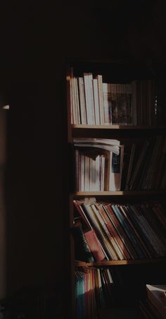 a bookshelf filled with lots of books in a dark room