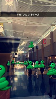 some people are walking through an airport with green inflatables on their heads