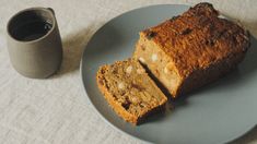 two slices of banana bread on a plate next to a cup of coffee