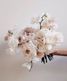 a bouquet of white and pink flowers is being held by someone's hand on a white background