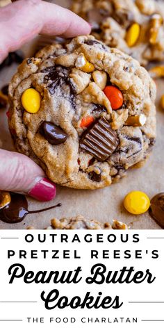 a close up of a person holding a peanut butter cookie with chocolate chips and candy