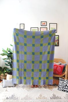 a blue and green blanket sitting on top of a bed next to a potted plant