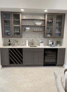 a kitchen with grey cabinets and tile backsplash, white counter tops and beige flooring