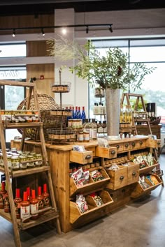 an assortment of food items on display in a store with wooden shelves and baskets filled with plants