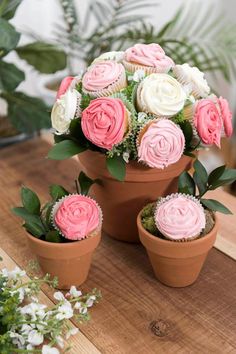 cupcakes in flower pots with pink and white frosting on them sitting on a table