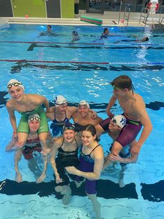 a group of people standing in a swimming pool next to each other with goggles on