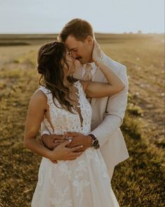 a bride and groom kissing in the middle of an open field at their wedding day