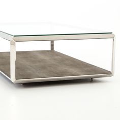 a glass and metal coffee table sitting on top of a white floor with no one around it