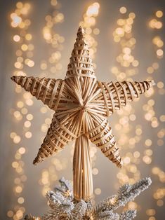 a wicker star ornament on top of a christmas tree with lights in the background