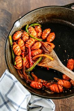 a skillet filled with cooked food on top of a wooden table next to a napkin