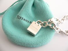 Overview: Here is a gift that she will surely adore! It is shiny, stylish, and super versatile! This piece will make someone REALLY happy! :) Offered for sale is a wonderful Tiffany & Co. Sterling Silver Signature Shopping Bag Charm Bracelet. Hanging from its bright Tiffany silver chain is a very pretty Shopping Bag charm with the words "Tiffany & Co" on it! A classic Tiffany piece that any girl will adore! Very pretty and just an adorable piece! It is simple, elegant, and classic all rolled int Luxury Silver Jewelry For Travel, Elegant Bracelets With Logo Charm As Gift, Luxury Bracelets With Logo Charm As Gift, Elegant Bracelets With Logo Charm For Gift, Designer Rectangular Bracelets As Gift, Luxury Rectangular Bracelet As Gift, Palladium Hardware Jewelry As Gift, Luxury Rectangular Bracelet Gift, Palladium Hardware Bracelets As Gift