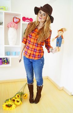 a young woman is standing in a room with sunflowers on the floor and holding a doll