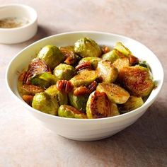 a white bowl filled with brussel sprouts next to two small bowls