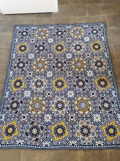 a blue and yellow area rug on the floor in a room with tile floors,