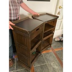 a man standing next to a wooden table with drawers on it's sides and one drawer open