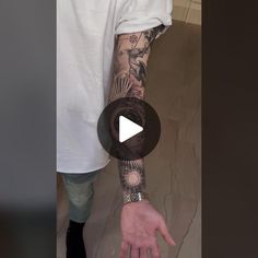 a man with tattoos on his arm and wrist is holding out his hand to the camera