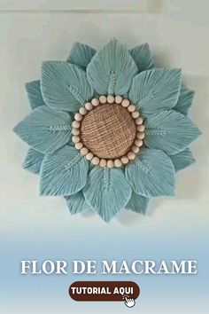 a blue flower made out of yarn and wood beads on the wall with text that reads flor de macrame