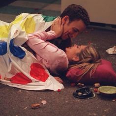 a man and woman laying on the ground next to each other with food all over them