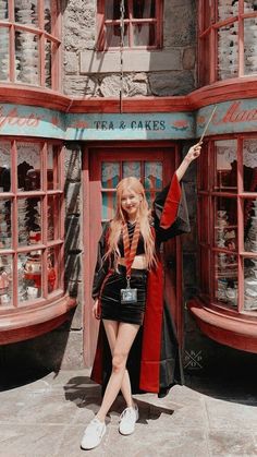 a woman standing in front of a store with her hand up to the camera and posing for a photo