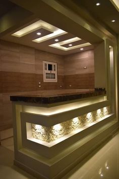 an empty room with lights on the ceiling and counter in front of it that is illuminated by recessed lighting