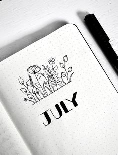 an open notebook with the word july written in black ink on it next to a pen