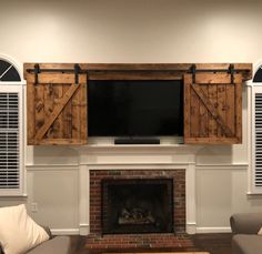 a living room with two couches and a television mounted on the wall over a fireplace