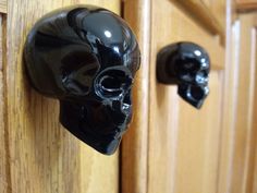 a black skull shaped door handle on a wooden cabinet