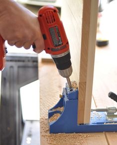 a person using a drill to attach wood