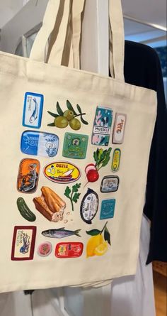 a tote bag with stickers on it hanging from a hook in a room