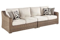 a wicker couch with pillows on it