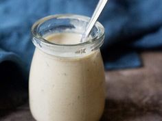 a glass jar filled with cream sitting on top of a wooden table next to a blue towel