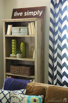 a living room filled with furniture and bookshelves next to a blue striped curtain