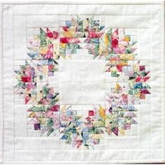 a quilted square with flowers and leaves in the center, on top of white paper