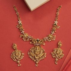 Description: This alluring necklace set from Tarinika features handcrafted designs decorated with temple elements surrounded with peacocks and flower motifs made of CZ stones and pearls on an antique gold base. Style this intricate temple set with any ethnic outfit. Details & Specifications:Materials used: Brass Alloy with Antique platingWeight - Necklace: 67 gms, Earrings: 29 gmsLength - Necklace: 19.5 cms, Earrings: 7.5 cmsMake it customWant to make it a custom necklace? Sure! Reach out to us Gold Necklace Set With Pearls, Antique Simple Necklace, Intricate Gold Necklace, Antique Gold Set Designs, Gold Necklace Designs For Bride, Gold Necklace With Earrings Set, Necleses Jewelry Gold Indian Latest, Tarinika Jewellery, New Model Necklace Designs Gold