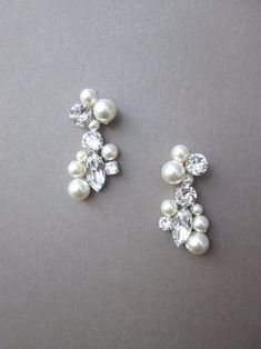 two pairs of pearl and crystal earrings on a gray surface, one with white pearls