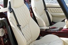 the interior of a car with white leather seats and steering wheel, along with water in the background